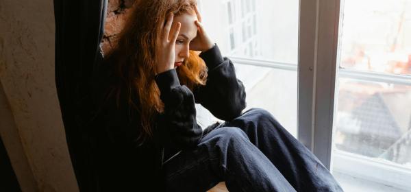 stressed woman sitting on window sill